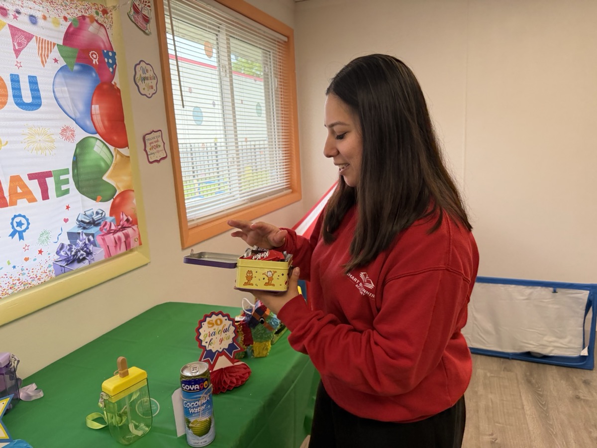 A teacher opening her personalized gift, smiling